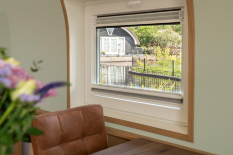 View from a window in a lodge at 't Landgoed Baars 1, Netherlands, with flowers and a brown chair.