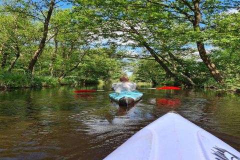 Two people kayaking down a scenic, tree-lined canal at 't Landgoed Baars 1 in the Netherlands.