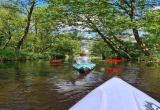Two people kayaking down a scenic, tree-lined canal at 't Landgoed Baars 1 in the Netherlands.