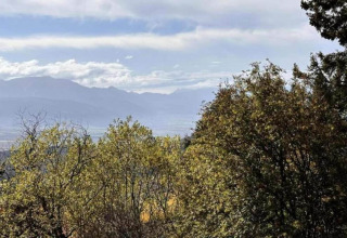 View of trees and mountains from the lodge 't Landgoed Baars 1 in the Netherlands on a partly cloudy day.