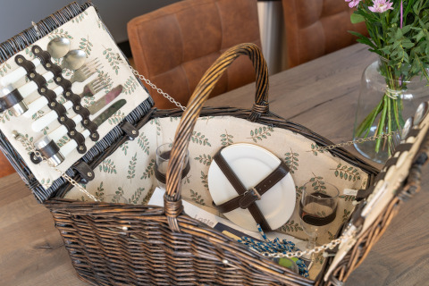 A beautifully arranged picnic basket with plates, cutlery, and glasses at 't Landgoed Baars 1, Netherlands.