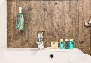 Badkamer met Rituals producten, kraan en houten wand bij Residence De Eese 3 in Nederland.