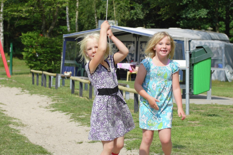 Twee meisjes spelen buiten bij chalet Residence de Eese 20 in Nederland op een zonnige dag.