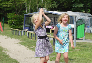 Twee meisjes spelen buiten bij chalet Residence de Eese 20 in Nederland op een zonnige dag.