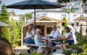 Fire personer sidder ved et udendørs bord under en parasol ved ferieboliger i Miedzyzdroje, Tyskland.