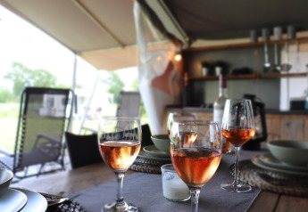 Set table with wine glasses in Safari tent 'Noflik' at a campsite in the Netherlands, cozy setup.