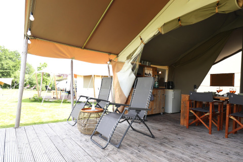 Safari-Zelt-Terrasse mit Liegestühlen, Esstisch und Blick ins Grüne – komfortables Camping-Erlebnis.