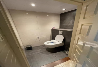 Modern bathroom with wall-mounted toilet and tiled walls inside Safari tent 'Noflik' in the Netherlands.