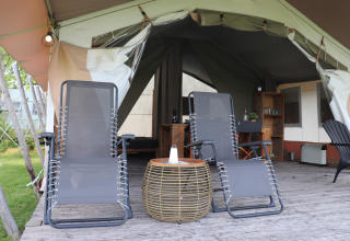 Deux chaises longues sur une terrasse en bois devant la tente safari « Noflik » avec intérieur cosy aux Pays-Bas.