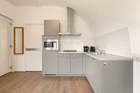 Cocina gris moderna en Water park De Bloemert 6, Países Bajos, con electrodomésticos empotrados y piso de madera.