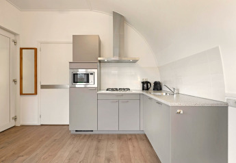 Modern grey kitchen at Water park De Bloemert 6 in the Netherlands, with built-in appliances and wooden floor.