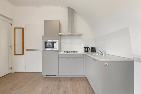 Cocina gris moderna en Water park De Bloemert 6, Países Bajos, con electrodomésticos empotrados y piso de madera.