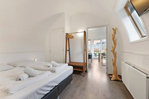 Helles Schlafzimmer in der Waterpark De Bloemert 6 Lodge, Niederlande, mit Doppelbett und Holzdeko.