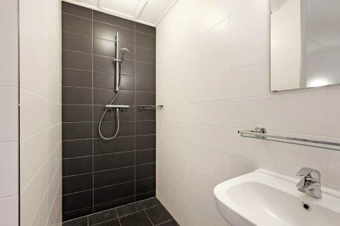 Ducha moderna con azulejos oscuros y lavabo en Water park De Bloemert 6 en los Países Bajos.