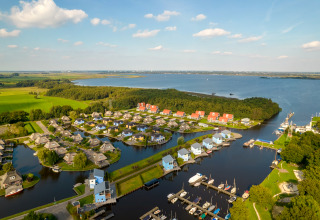 Luftaufnahme einer Lodge am See mit modernen Häusern, Bootsstegen und viel grüner Landschaft drumherum.