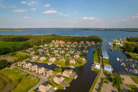 Aerial view of peaceful lodges by the waterfront with green landscapes and boats moored at a marina.