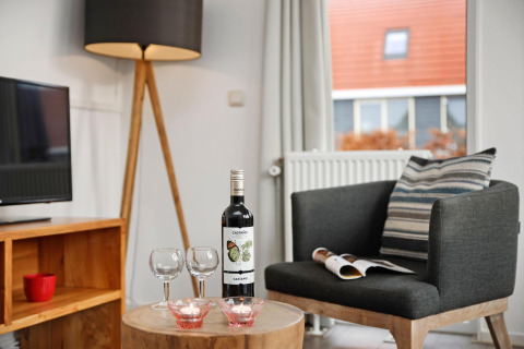 Gemütliche Sitzecke im Water park De Bloemert 6 in den Niederlanden mit Wein, Gläsern und TV.