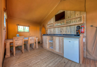 Interieur van safaritent met houten meubilair, kitchenette en eethoek, Holiday park Hunzedal 15, Nederland.