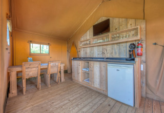 Interno di una tenda safari con arredi in legno, angolo cucina e tavolo da pranzo, Holiday park Hunzedal 15, Olanda.