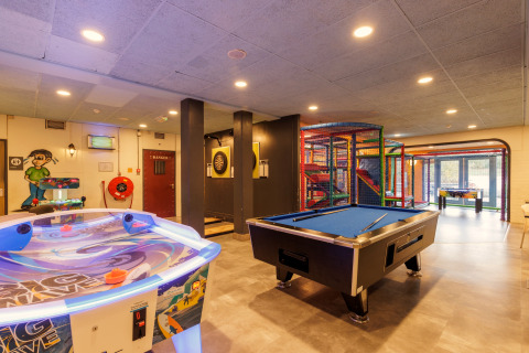 Speelkamer in een safaritent met pooltafel, airhockey, dartbord en kleurrijke speelzone voor kinderen.