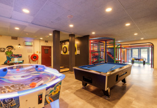 Spelruimte bij een safaritent met pooltafel, airhockey, dartbord en kinderspeeltuin binnen.