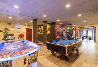 Sala giochi interna in una tenda safari con biliardo, air hockey, freccette e area giochi bambini.