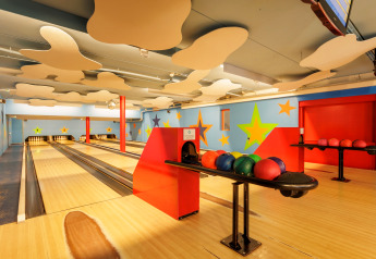 Børnevenlig bowlingbane indendørs med farverige stjerner på væggene og bowlingkugler klar til spil.
