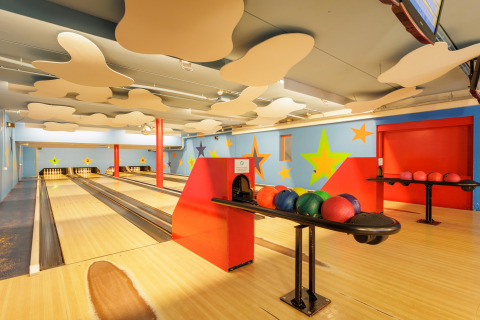 Pista de bolos cubierta y colorida, decorada con estrellas y bolas listas para jugar en familia.