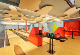 Børnevenlig bowlingbane indendørs med farverige stjerner på væggene og bowlingkugler klar til spil.