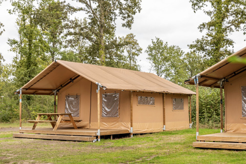 Tenda safari con terrazza in legno e tavolo al Holiday park Hunzedal, immersa nel verde.