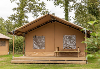 Tienda safari en el parque vacacional Hunzedal 15 en Países Bajos, con terraza y banco de madera.