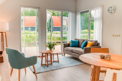 Bright, modern living room at Water park ‘De Bloemert 7’ in the Netherlands with garden views.