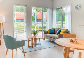 Bright, modern living room at Water park ‘De Bloemert 7’ in the Netherlands with garden views.