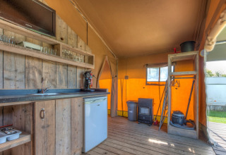 Interno di una tenda safari a Holiday park Hunzedal 15, Paesi Bassi, con cucina in legno rustico.