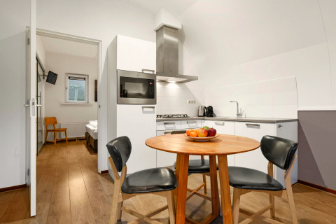 Modern kitchenette and round dining table with three chairs at Water park «De Bloemert 7», Netherlands.