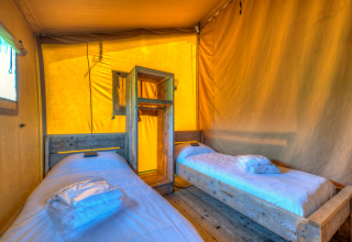 Binnenzicht van een safaritent slaapkamer met twee eenpersoonsbedden bij Holiday park Hunzedal 15, Nederland.