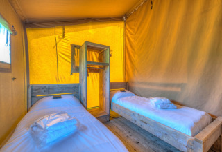 Vista interna di una tenda safari con due letti singoli all'Holiday park Hunzedal 15 nei Paesi Bassi.