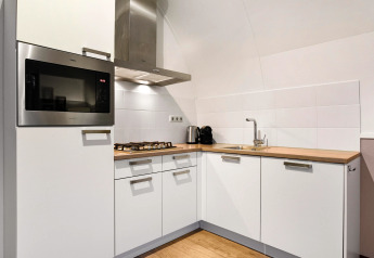 Angolo cucina moderno al Water park «De Bloemert 7» nei Paesi Bassi con mobili bianchi e piano in legno.