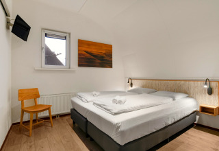Camera moderna al lodge Water park De Bloemert 7 nei Paesi Bassi, con letto matrimoniale e sedia in legno.