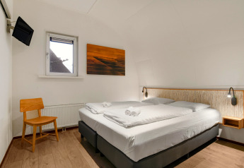 Camera moderna al lodge Water park De Bloemert 7 nei Paesi Bassi, con letto matrimoniale e sedia in legno.