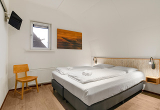 Habitación moderna en la cabaña Water park De Bloemert 7 en los Países Bajos, con cama doble y arte mural.