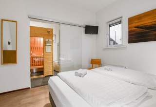 Dormitorio en Water park «De Bloemert 7» en Países Bajos con sauna, cama doble y decoración moderna.