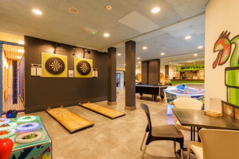 Recreatieruimte in safaritent met dartborden, airhockey, pooltafel en kleurrijke decoratie.