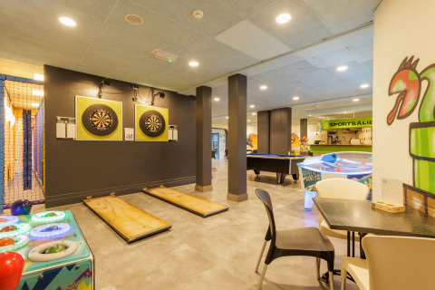 Sala de juegos en tienda safari con dardos, air hockey, billar y decoración moderna y colorida.