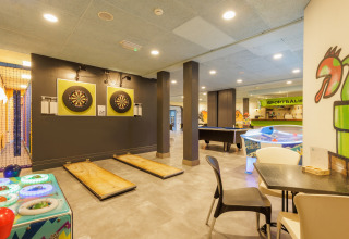 Salle de jeux sous tente safari avec fléchettes, air hockey, billard et une décoration colorée.