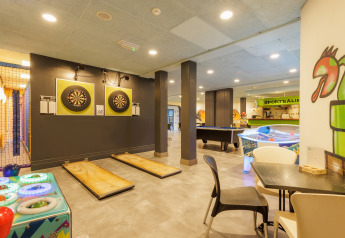 Sala de juegos en tienda safari con dardos, air hockey, billar y decoración moderna y colorida.