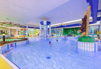 Piscina cubierta decorada con temática de safari, figuras de animales y murales coloridos.
