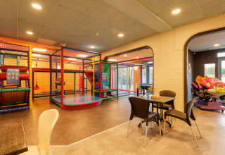 Binnen speelzone met klimtoestel, miniauto en zitplaatsen bij een safaritent voor gezinnen.