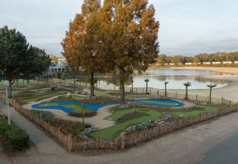 Foto de un campo de minigolf junto a un lago, vista desde una tienda safari, rodeada de arena y árboles.