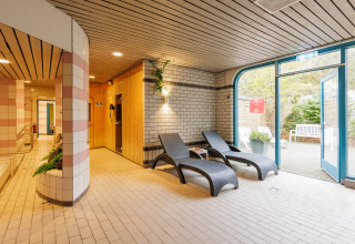 Zona relax interna in una tenda safari con lettini prendisole, sauna e accesso al giardino di giorno.